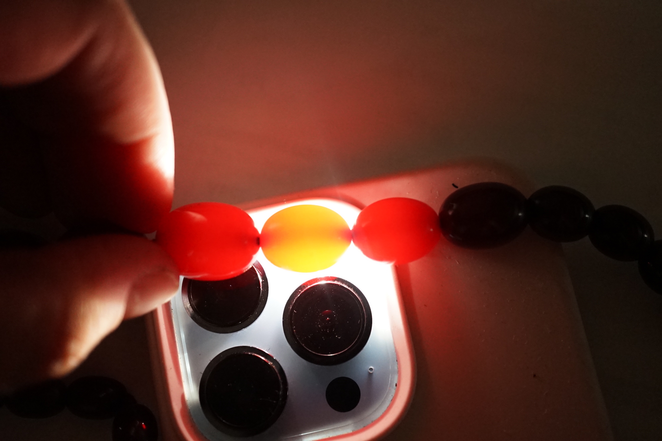 A single strand graduated simulated cherry amber necklace, one other necklace and some loose beads